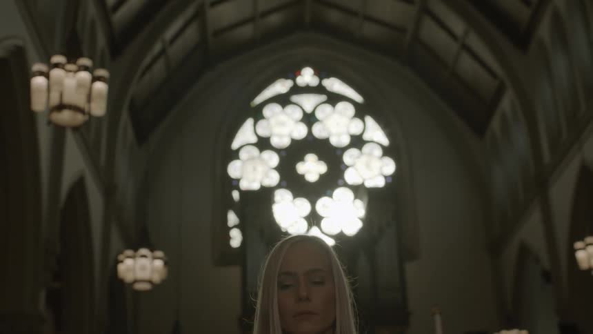 A woman stands alone in a church