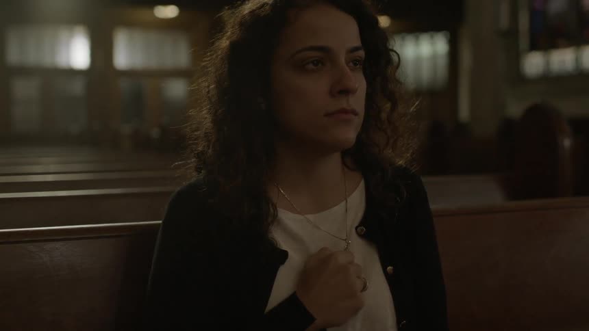 Woman sitting in church holding her necklace