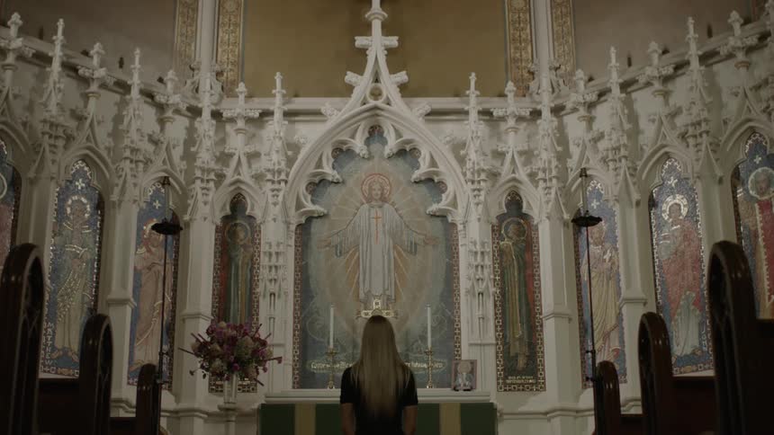 Woman standing in church facing a mural of jesus