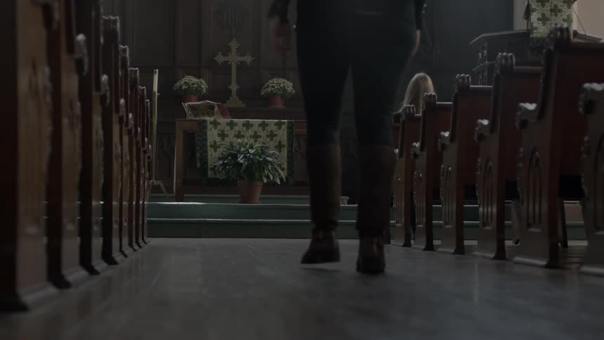 A woman walks up the aisle of a church