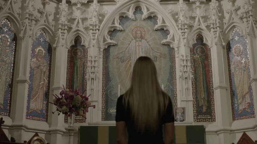 Woman standing in church facing a mural of jesus