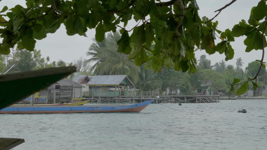 Island huts on a shore lined up next to a pier next to the coast