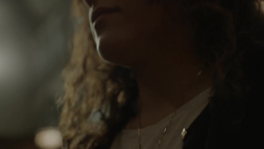 Woman touching her cross necklace and then staring out forward