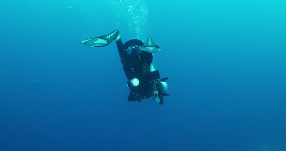 A scuba diver is using a motor to propel him faster underwater