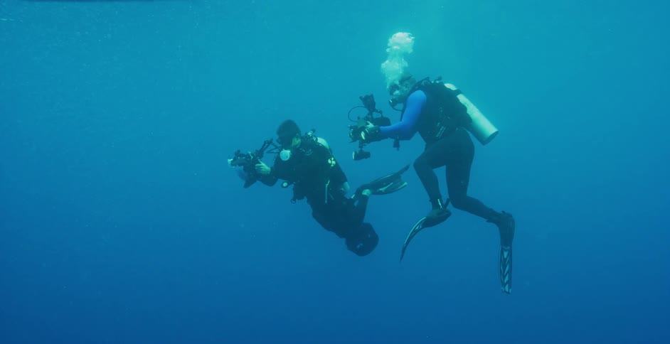 A pair of divers take footage underwater with underwater cameras