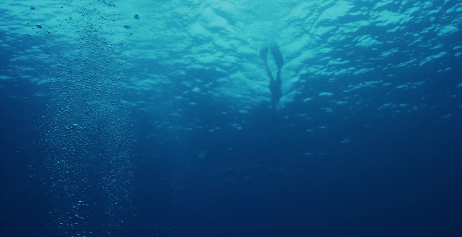 A diver swimming away from a boat under water
