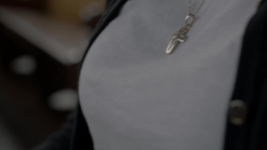 Woman wearing a cross necklace looking down at a bible