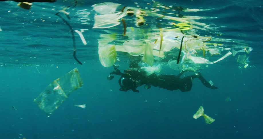 A diver swimming with rubbish filming with camera equipment