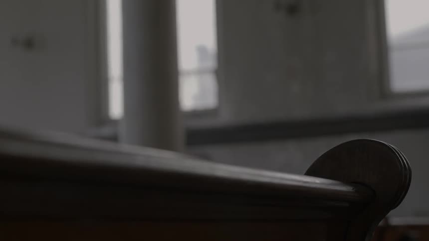 A female walks around and sits in a church pew