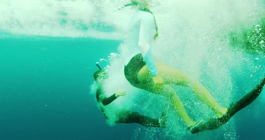 A man and woman jump off a boat in to the water