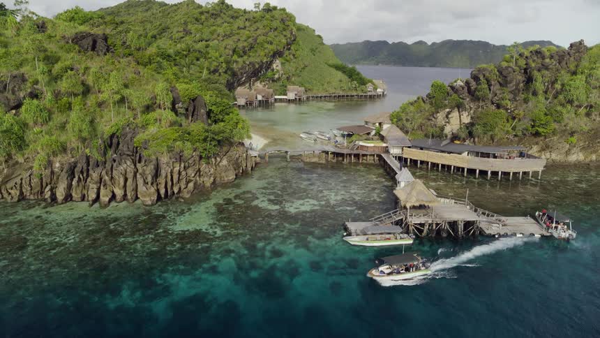 A boat leaves a dock from a set of islands in the ocean