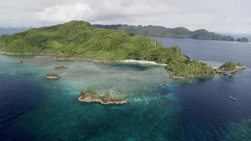 Aerial view of islands with blue water and coastlines with one boat in the water at daytime