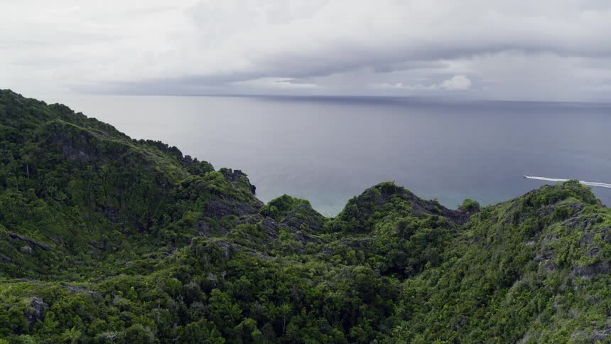 A seacraft travels through the ocean off the mountainous coast of a landmass