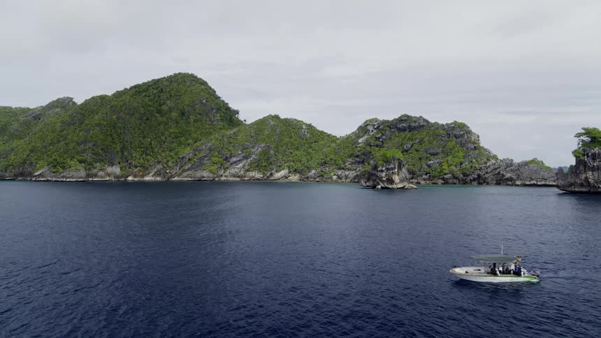 A boat floating by a tropical island on dark blue ocean water
