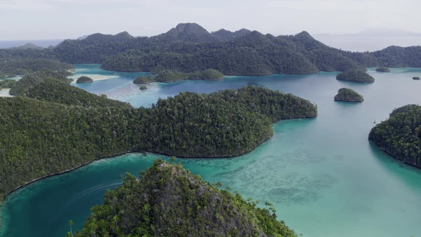 Aerial view of large islands with tall mountains and small coastal shores surrounded by ocean