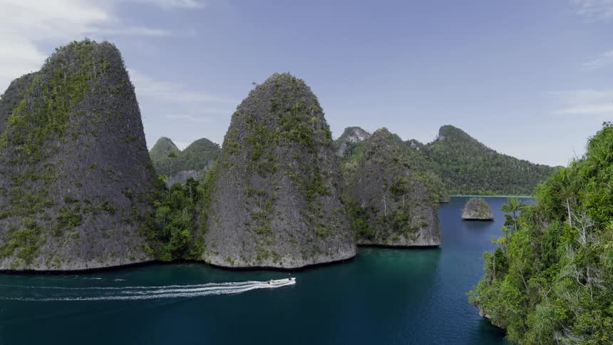 A boat floating by tropical island mountains in the daytime