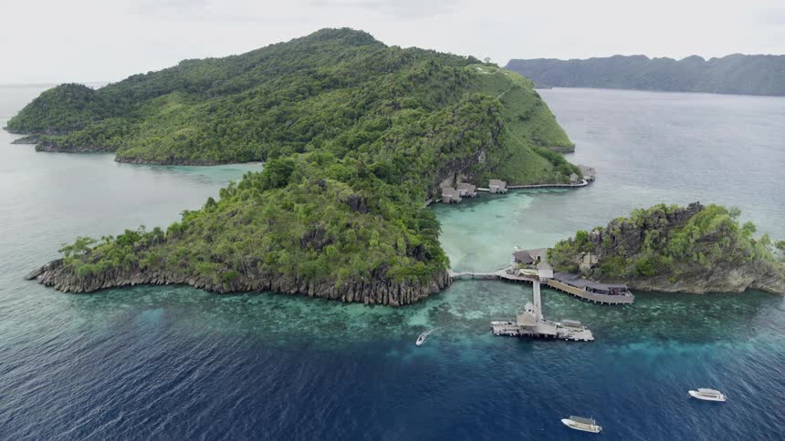 The green island is being left behind as the boat travels away from it