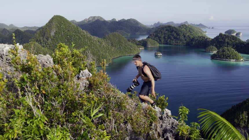 Man climbing an island cliff peak in an archipelago