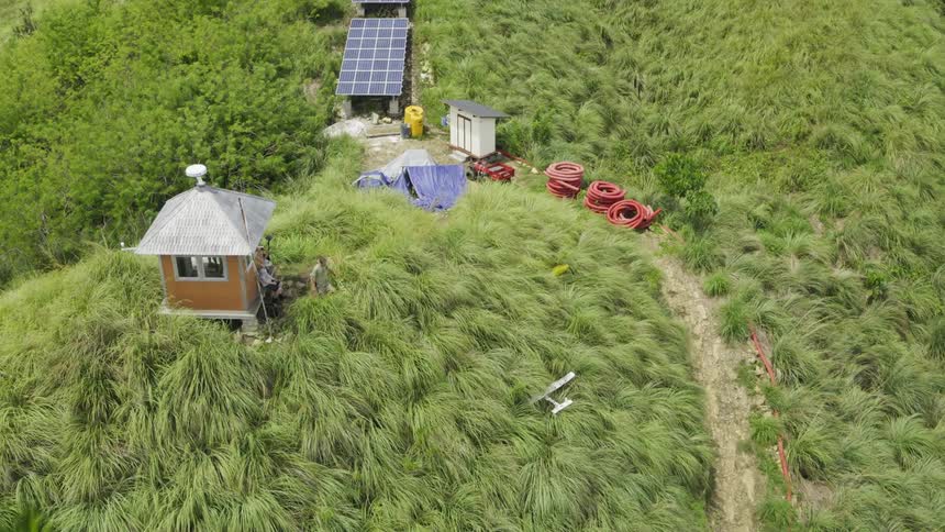 A small white plane is crashed into bushes near a tiny house along the coast