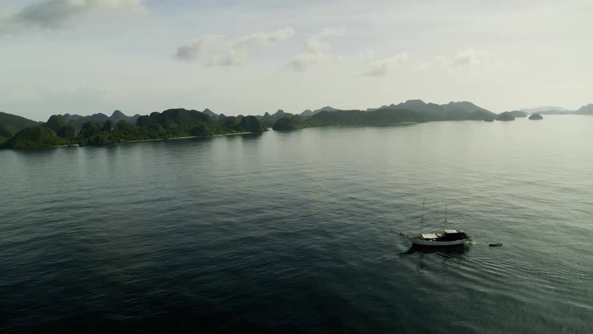 A boat is on a body of water with land in the background