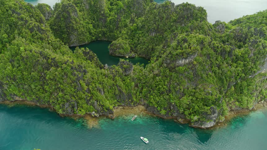 Aerial view of tropical island against water with two boats in foreground