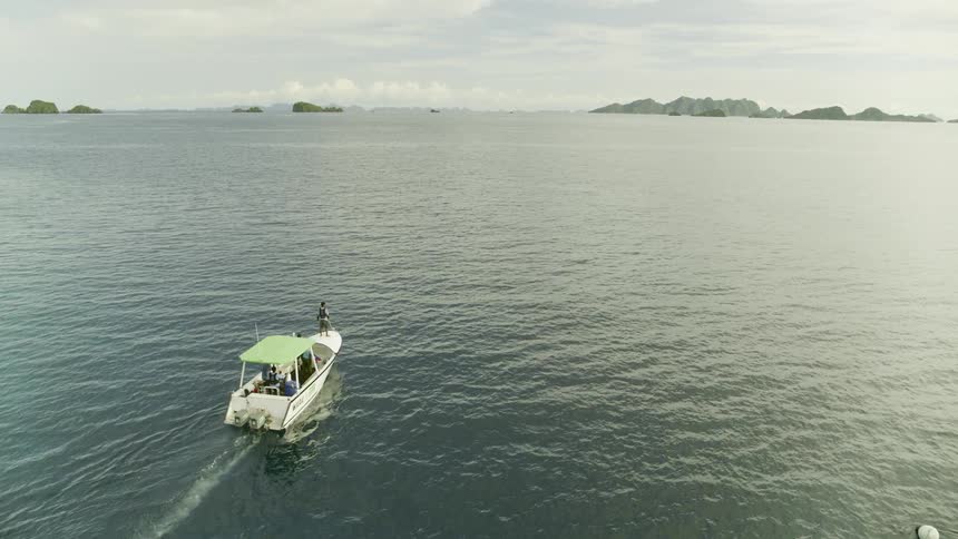 Boat with people sailing out at sea surrounded by small islands