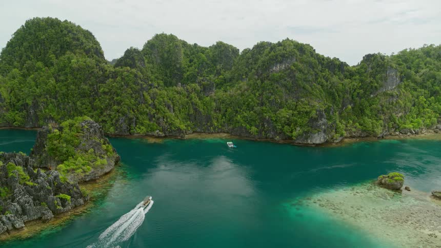 Islands out in the middle of the ocean with small boats sailing by