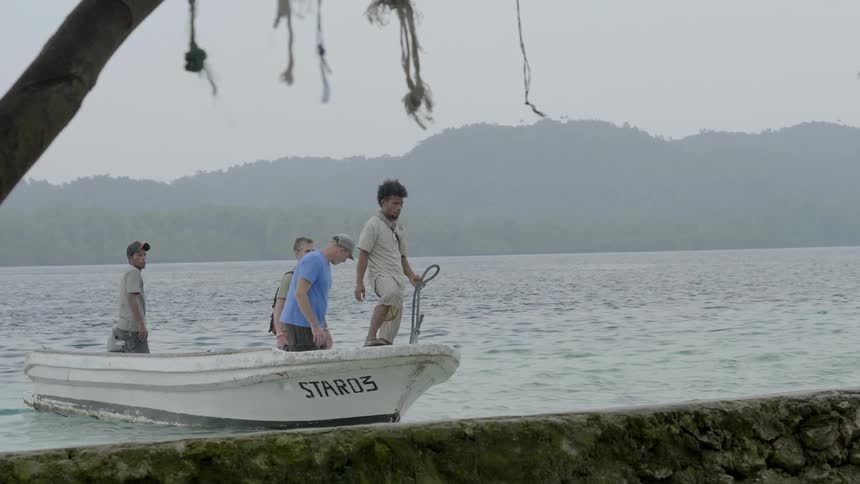 A group of men come to shore on a small boat