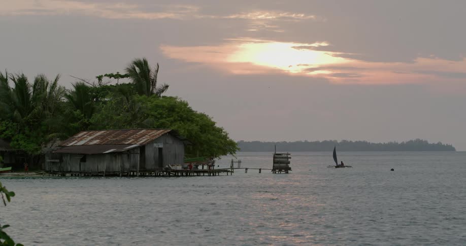 Shanty hut on the coast of an island next to a sunset over the ocean