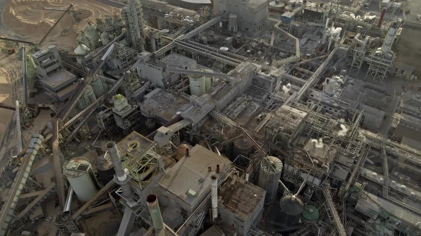 Aerial view of a massive industrial facility as smoke and steam emerge from multiple smokestacks