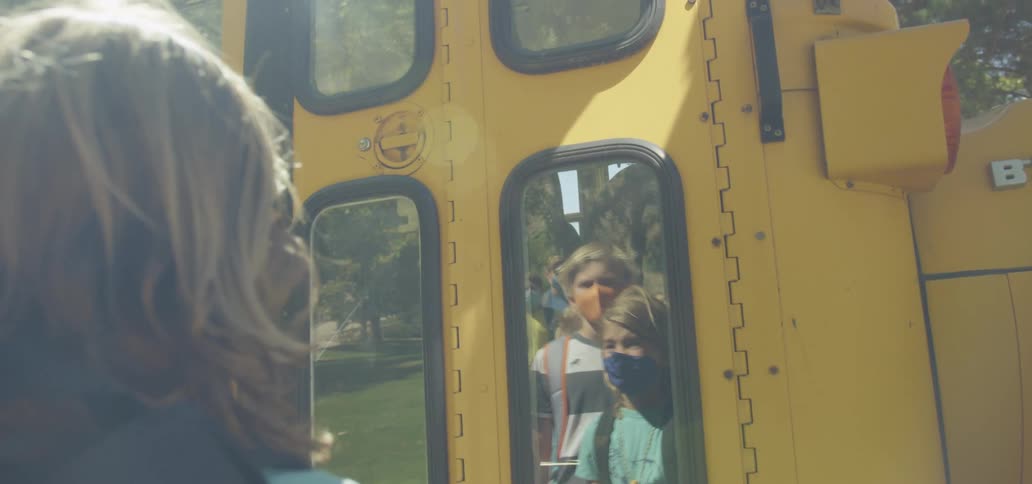 A school bus arrives at a bus stop and the waiting children board the bus