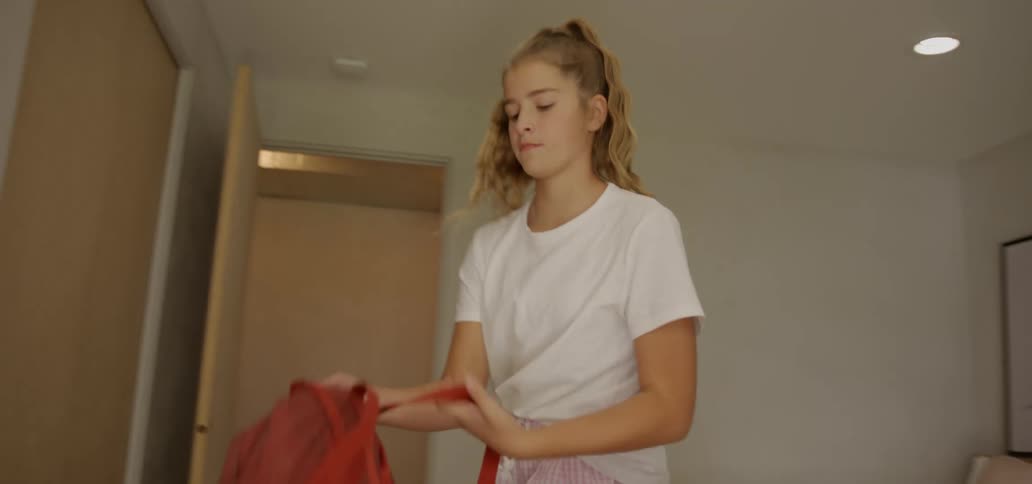 Blonde teenage girl takes off headphones and leaves the room taking her backpack