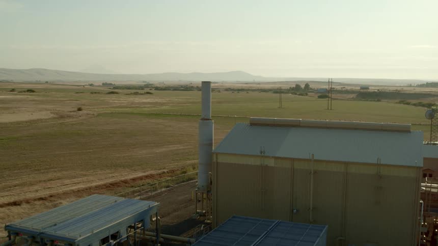 Pullback descent reveal of a natural gas pumping facility surrounded by open countryside