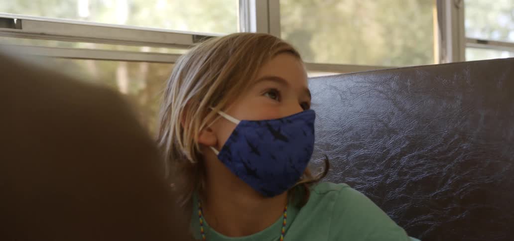 A girl with a mask sitting on a school bus