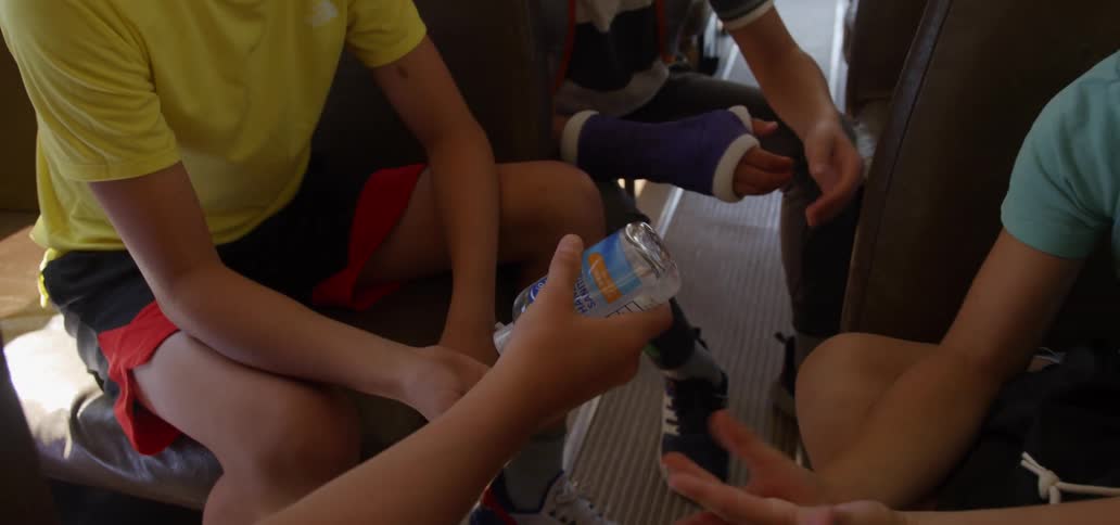 Kids sitting on a bus put hand sanitizer on