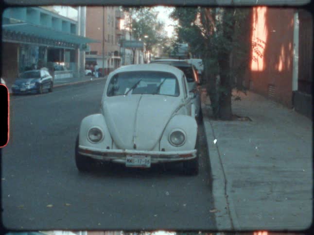 An old fashioned vehicle parked beside the curb in a city during the day