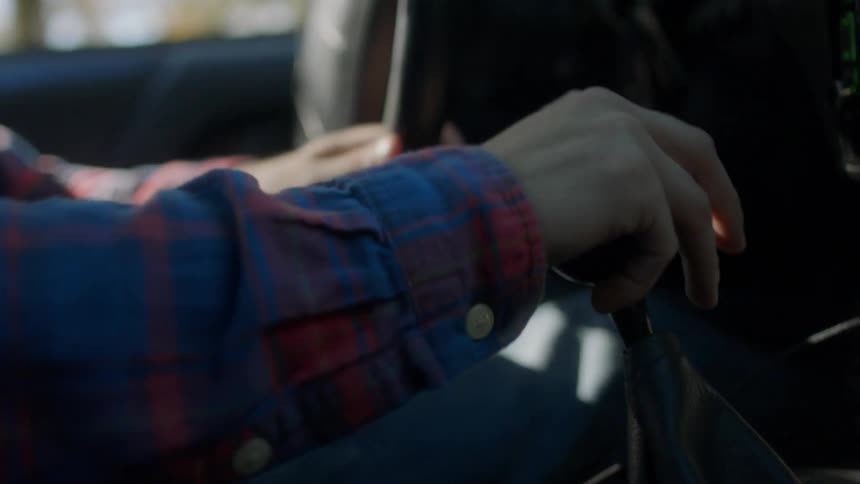 Hand driving a stick shift car inside of a moving vehicle