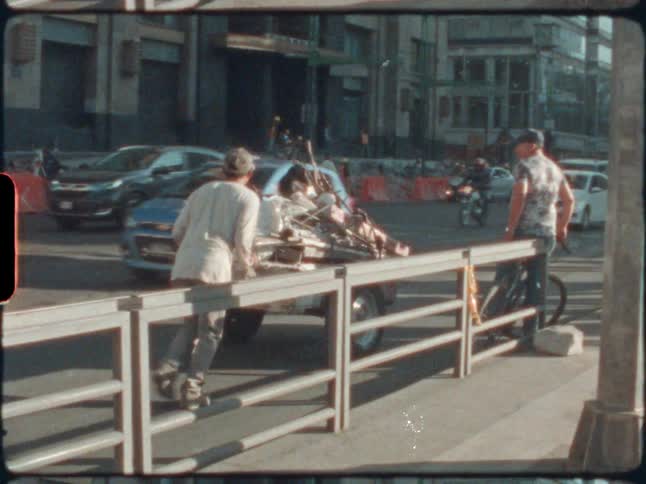 A man pushes a cart next to a busy street