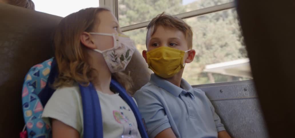 Children wearing face masks riding on a bus