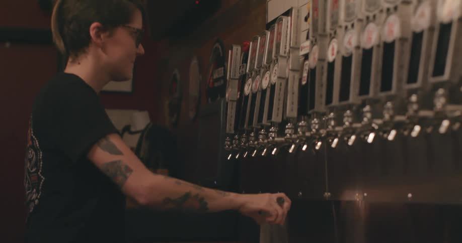 Female bartender filling glasses with alcohol in a bar