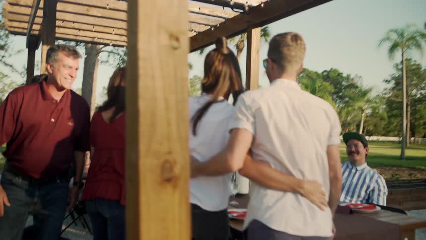 Family greeting each other and hugging next to a table in the park