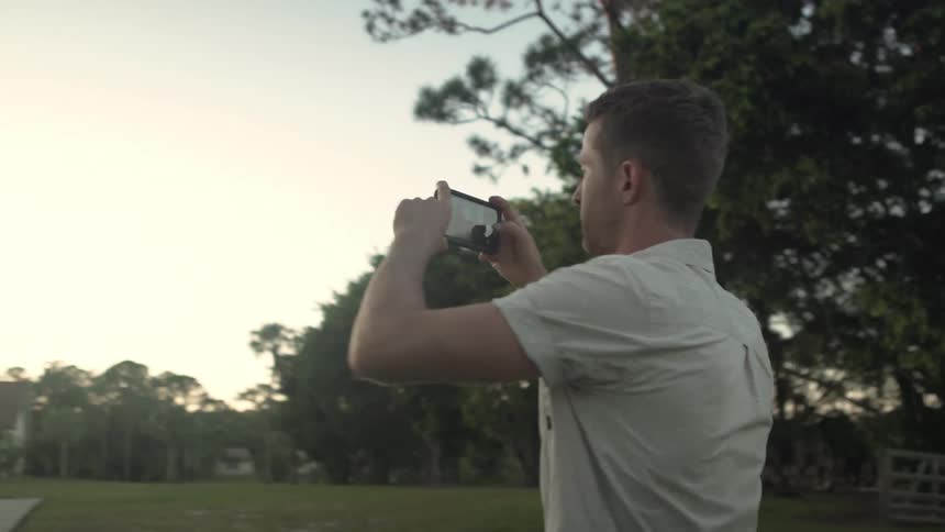 A man is taking a photo of an outdoor setup for an event at sunset