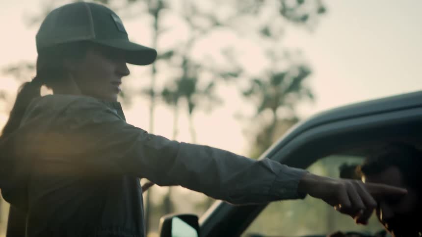 A man and woman are by a car at dusk