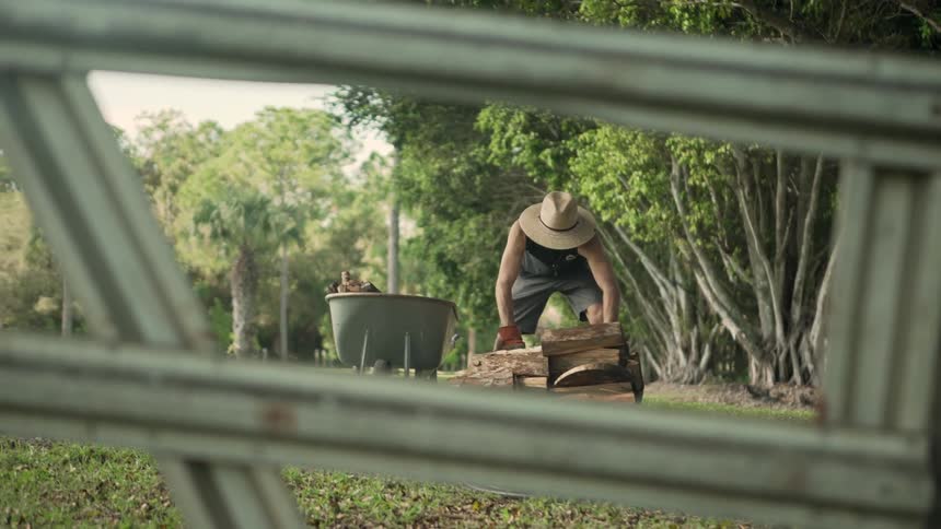 A man is loading wood into a wheel barrel