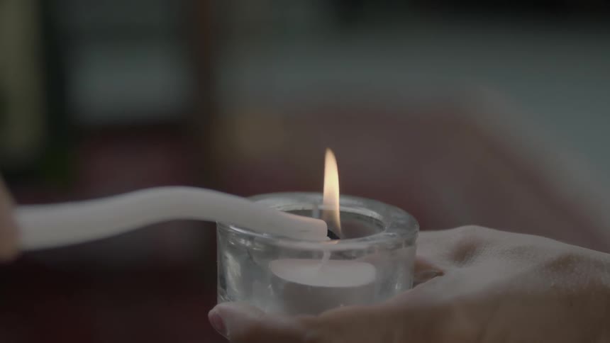 A candle is lit in a small jar
