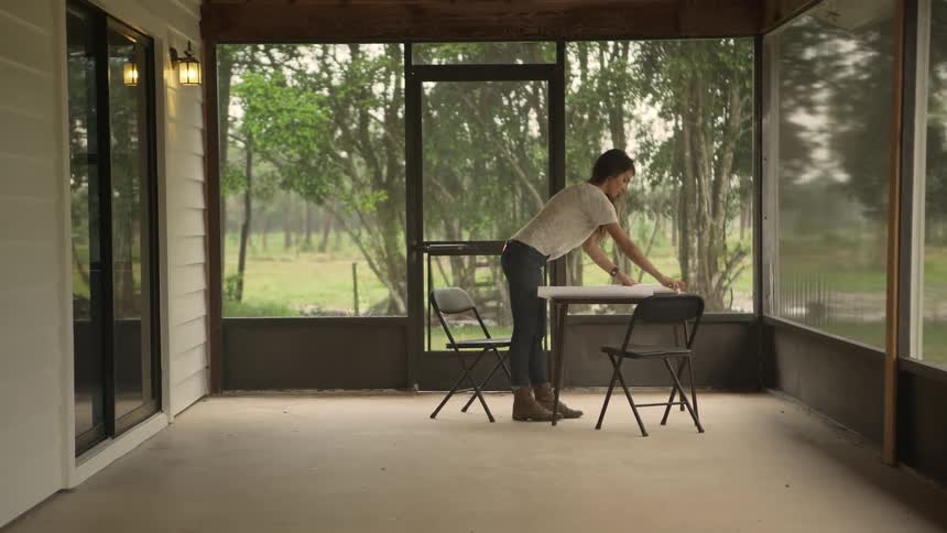 Woman standing in a patio preparing paperwork on a small table