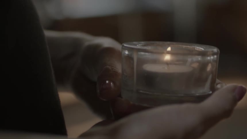 A woman holds a burning votive in her hands