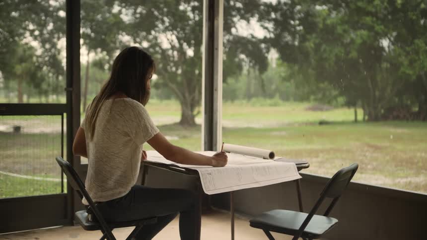 Woman sitting at a table writing on a paper and reading