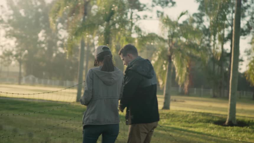 Two people putting up a fence in a rural area