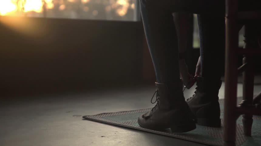 A person is tying their shoes indoors